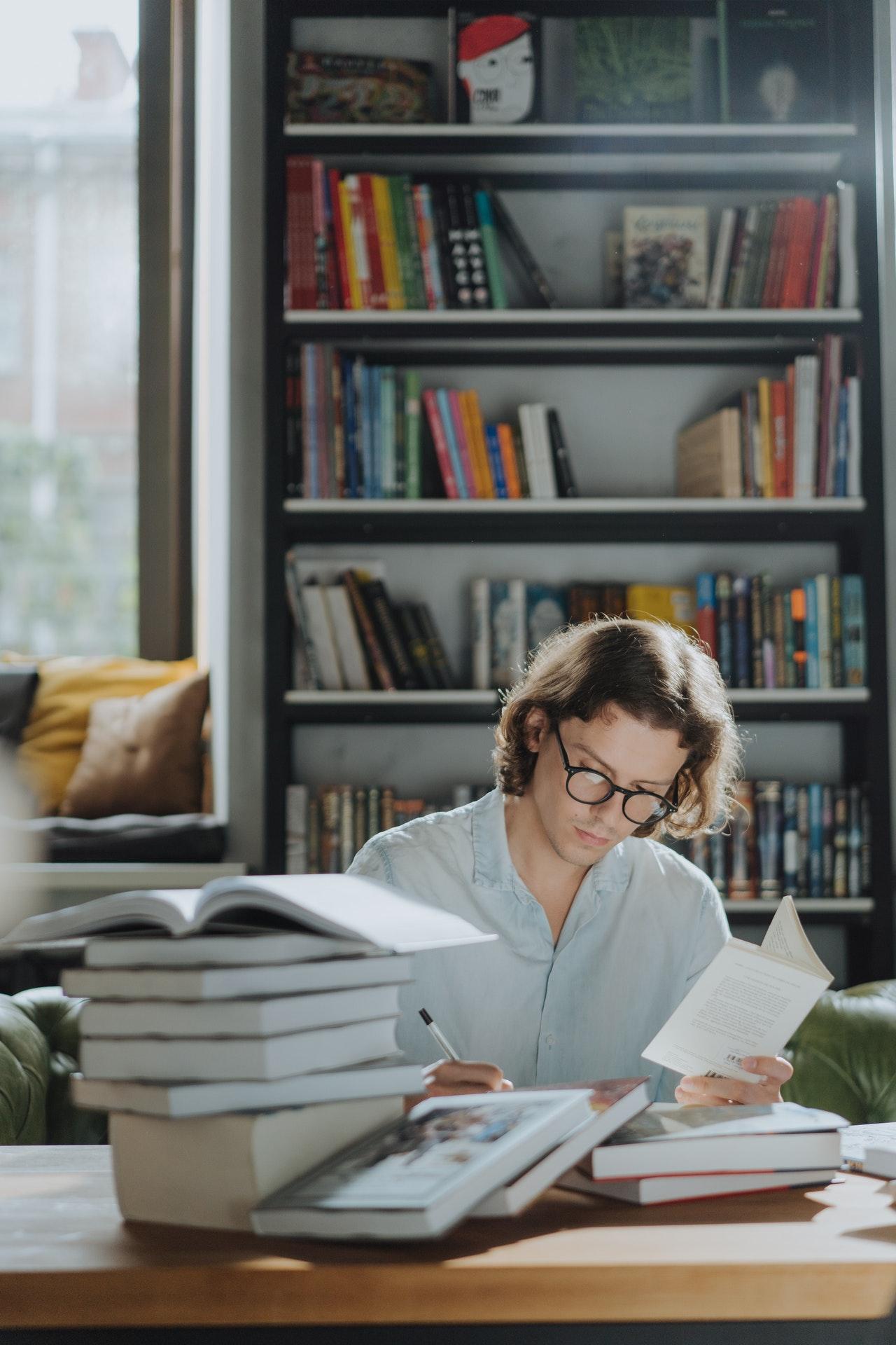 Ein Mann sitzt am Tisch mit Büchern und liest