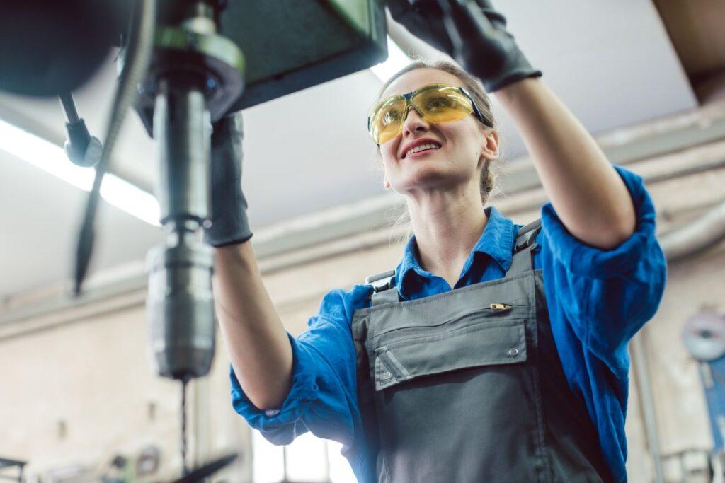 Mitarbeiterin der Schlosserei Freiburg arbeitet konzentriert an einer Bohrmaschine in einer professionellen Werkstattumgebung.