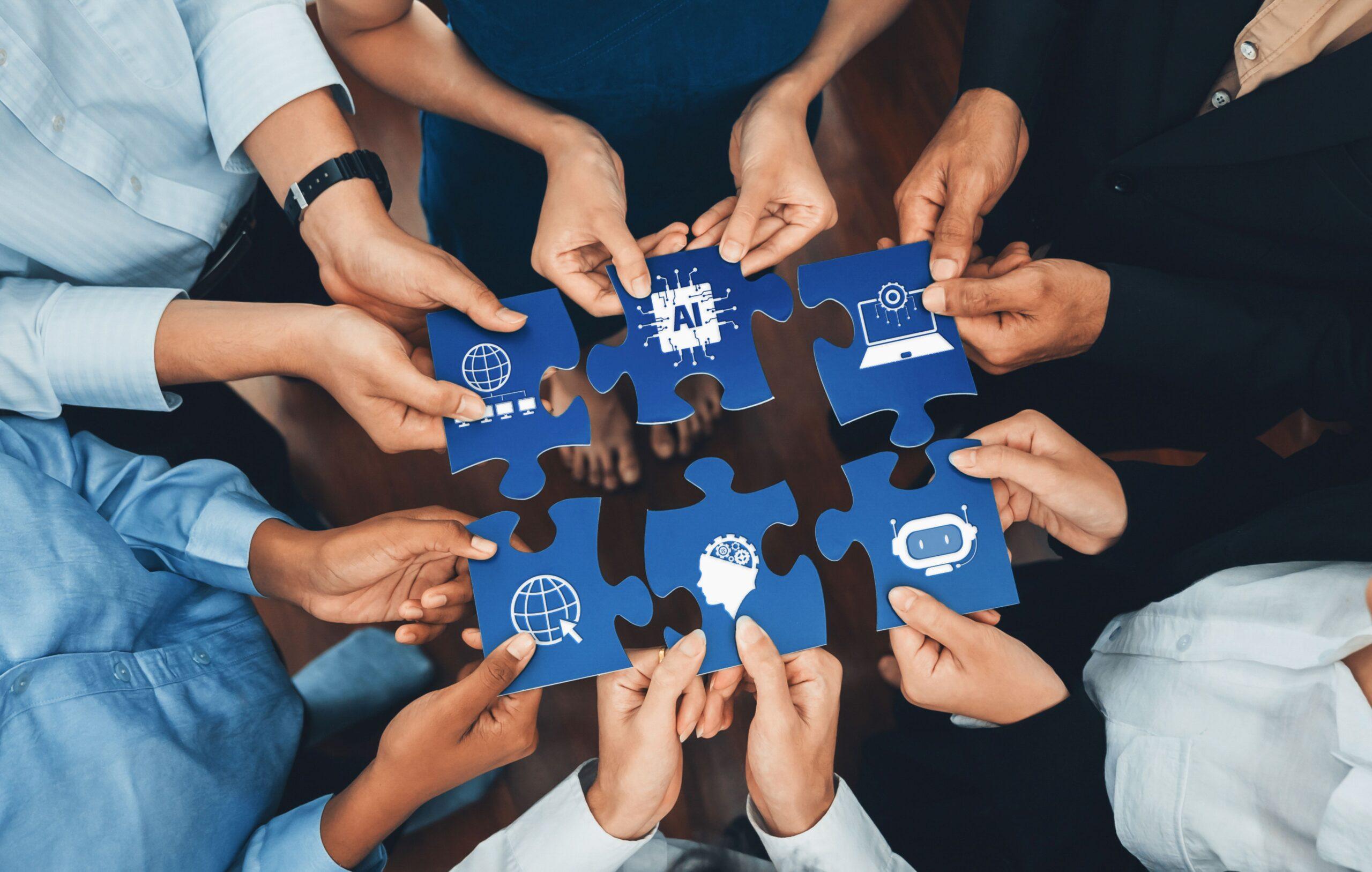 Verschiedene Menschen halten Puzzleteile mit Symbolen für KI Lösungen, Zusammenarbeit und Digitalisierung
